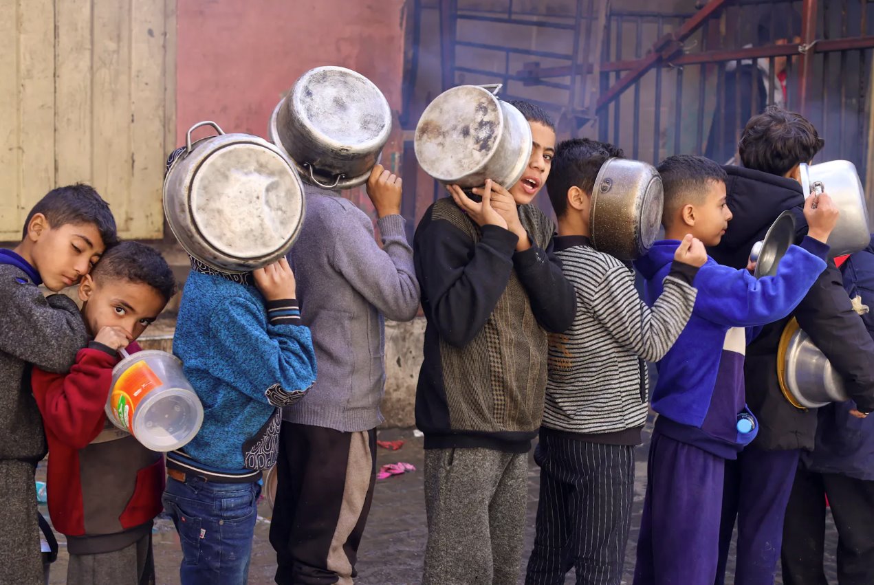 2023年12月14日，在加沙地帶南部的拉法，隨著以色列和哈馬斯之間的沖突持續，巴勒斯坦兒童拎著鍋排隊領取慈善廚房烹制的食物，沖突繼續導致糧食供應短缺。