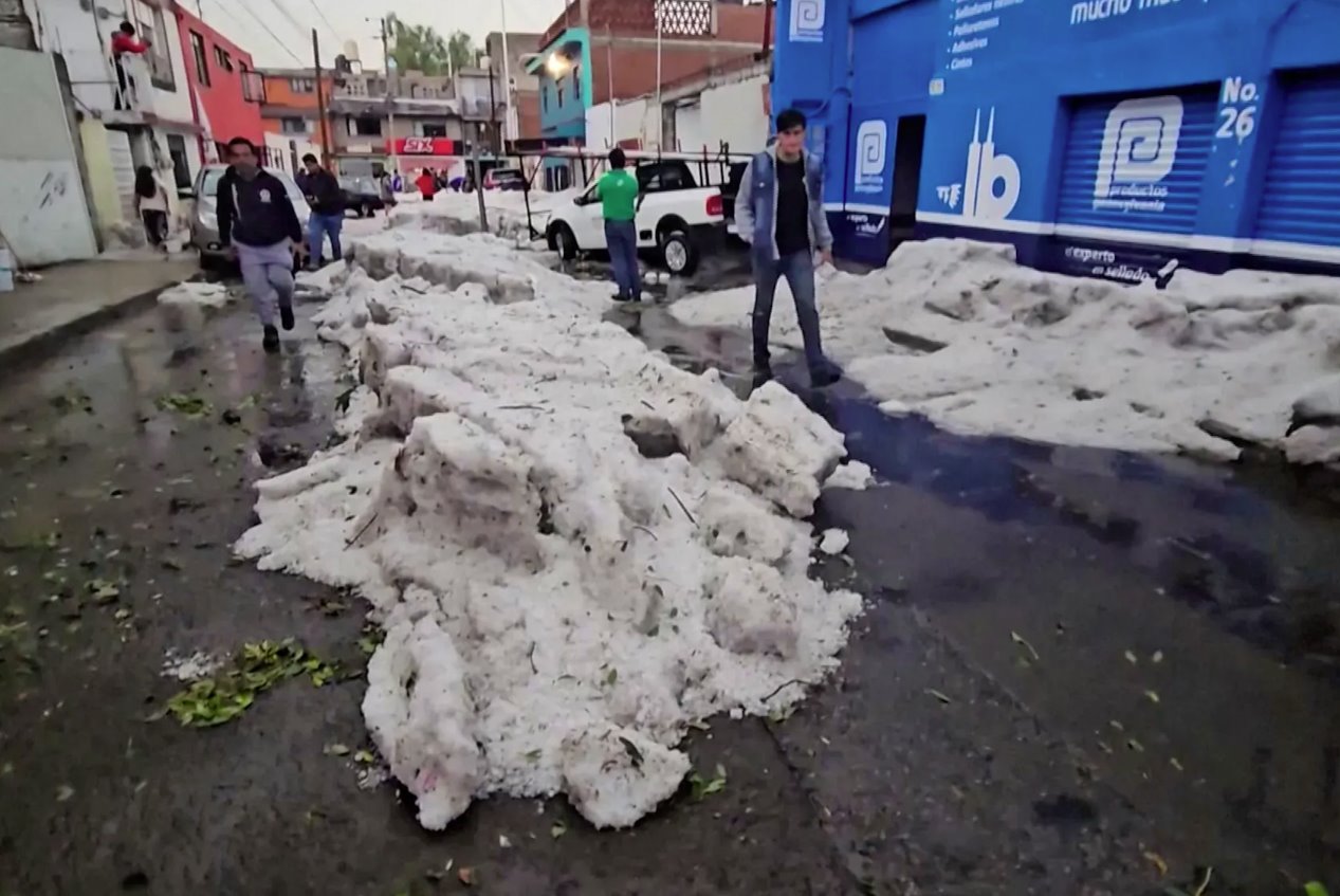 2024年5月24日,墨西哥普埃布拉,熱浪中的冰雹過后,人們在厚冰旁行走。