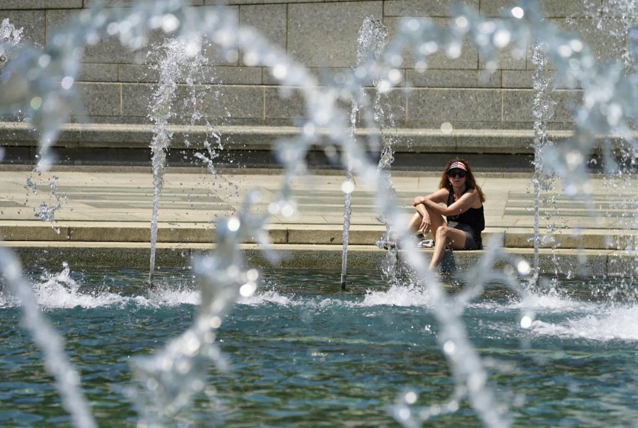 2024年4月29日，美國華盛頓，在可能創(chuàng)紀(jì)錄的高溫日，一名戴著星條旗遮陽帽的女士將腳浸入二戰(zhàn)紀(jì)念館的涼爽噴泉中。